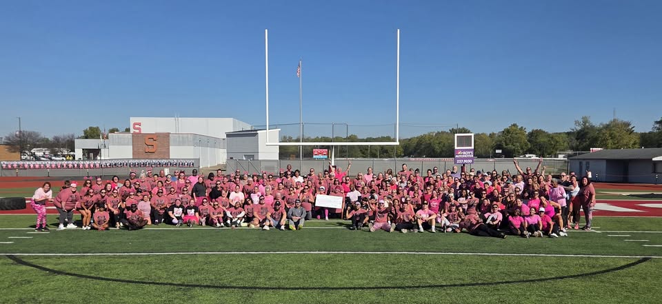 School Fit Challenge participants and coaches in pink shirts gathered on a football field